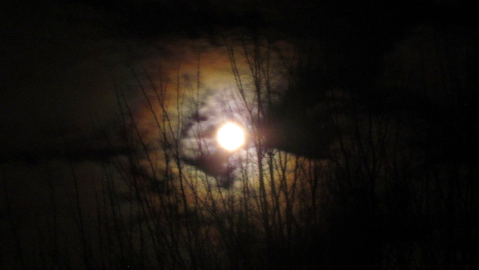 Kleurige rand om de maan tussen de wolken