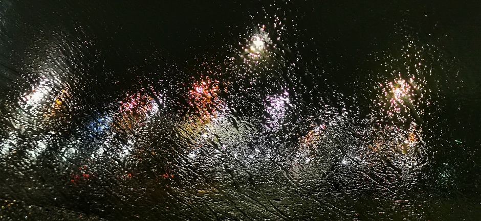 Regen op de autoruit midden in de nacht maakte van de lampen een soort kunstwerk 