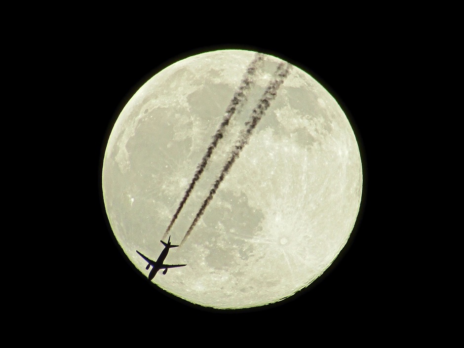 Volle maan met passerend vliegtuig