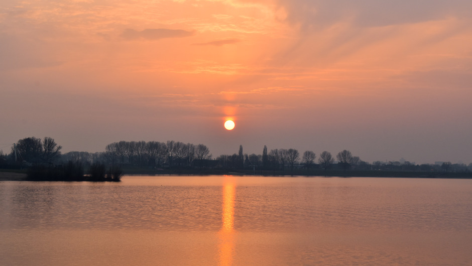 Zonnezuil tijdens zonsondergang boven de Rhederlaagse meren in Lathum