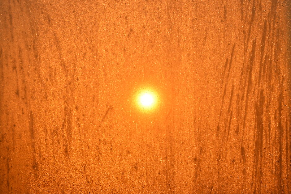 De zon door een raam met mistdruppels