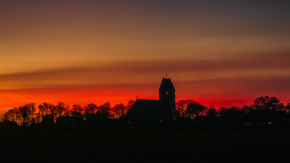 Prachtige rode kleuren kwamen in de lucht na zonsondergang kerkje in Hollum