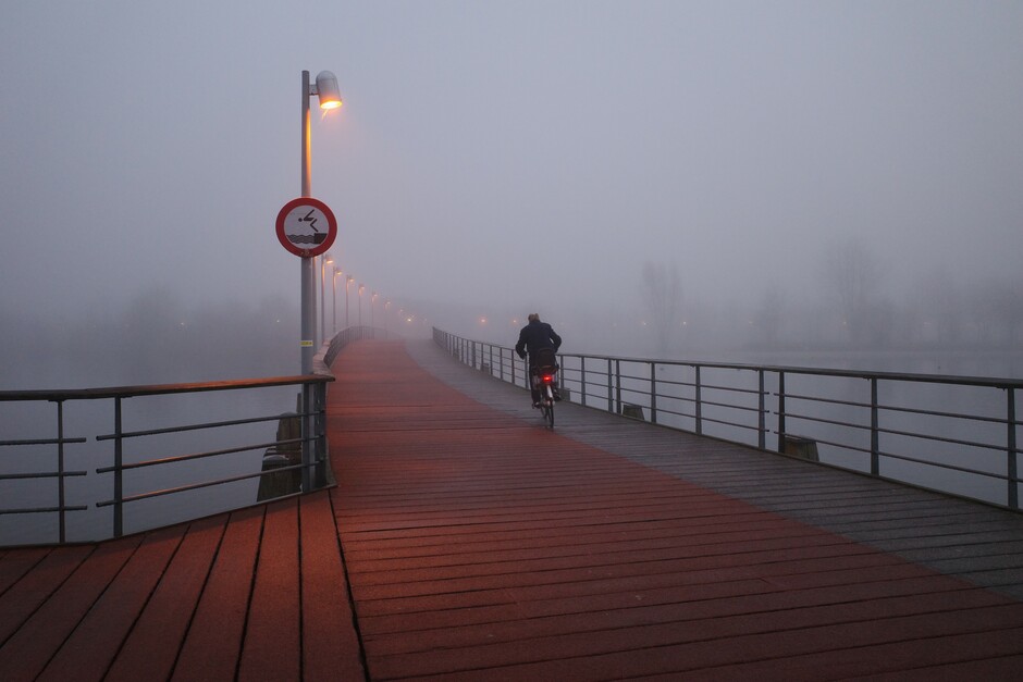 Fietser in de mist op fietsbrug