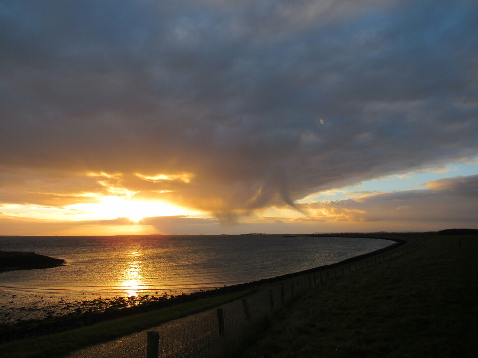 Zonsopkomst bij Kats, Zeeland, dikke donkere wolkenlaag waar neerslag uitviel, maar de zon kwam eronder vandaan