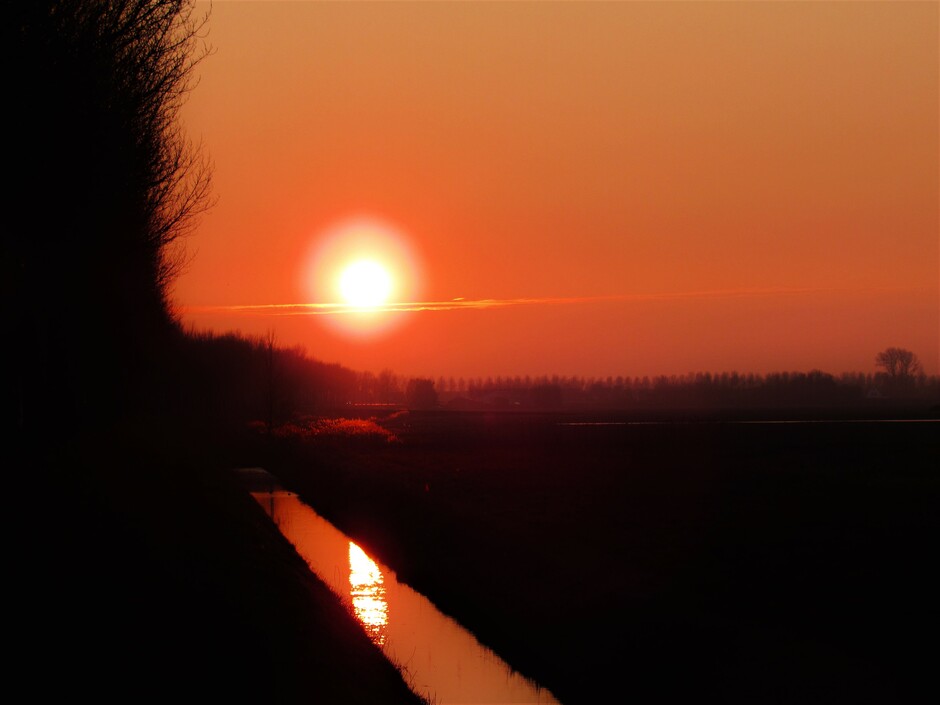 Oranje zonsondergang met een laag mist boven de grond
