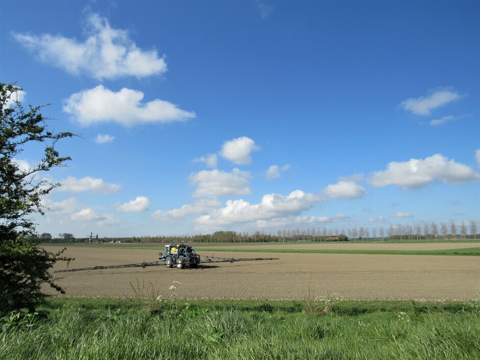 Druk op het land met boeren die hun land bewerken, zon, wolken en een windje