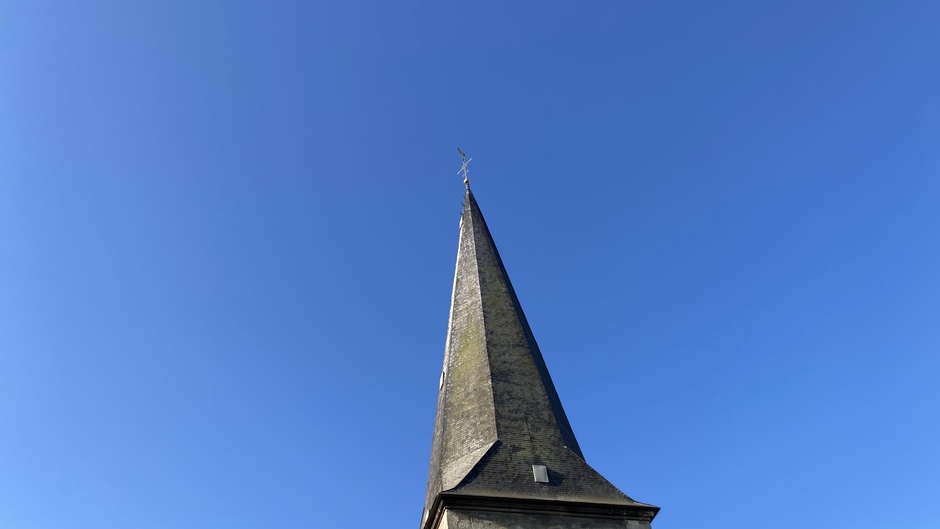 Tijdloze kerktoren in de blauwe zonnige lucht
