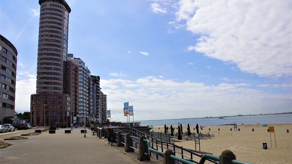 zon blauwe lucht bewolking 20 gr aan het strand met boulevard terras/strand  weer