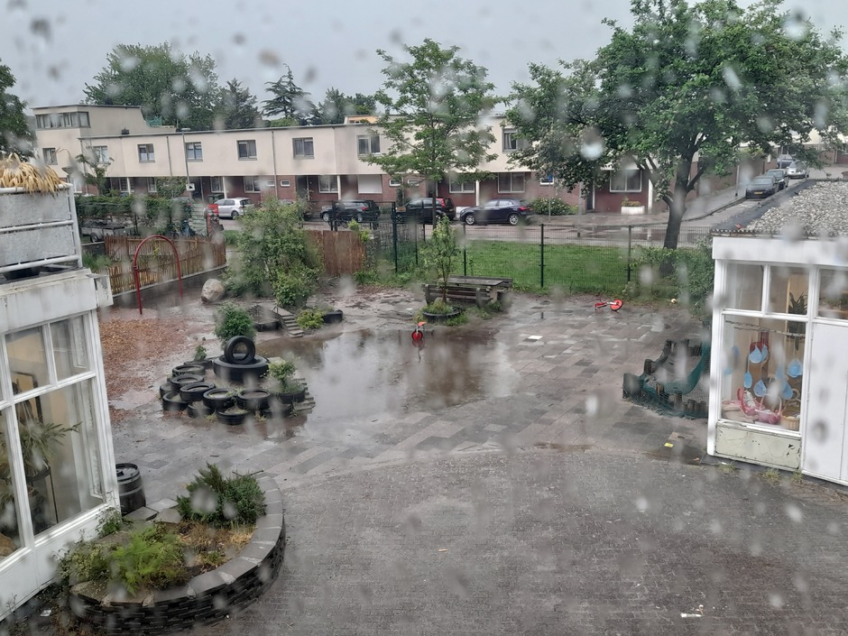 Veel regen en en flinke plas water op het schoolplein.