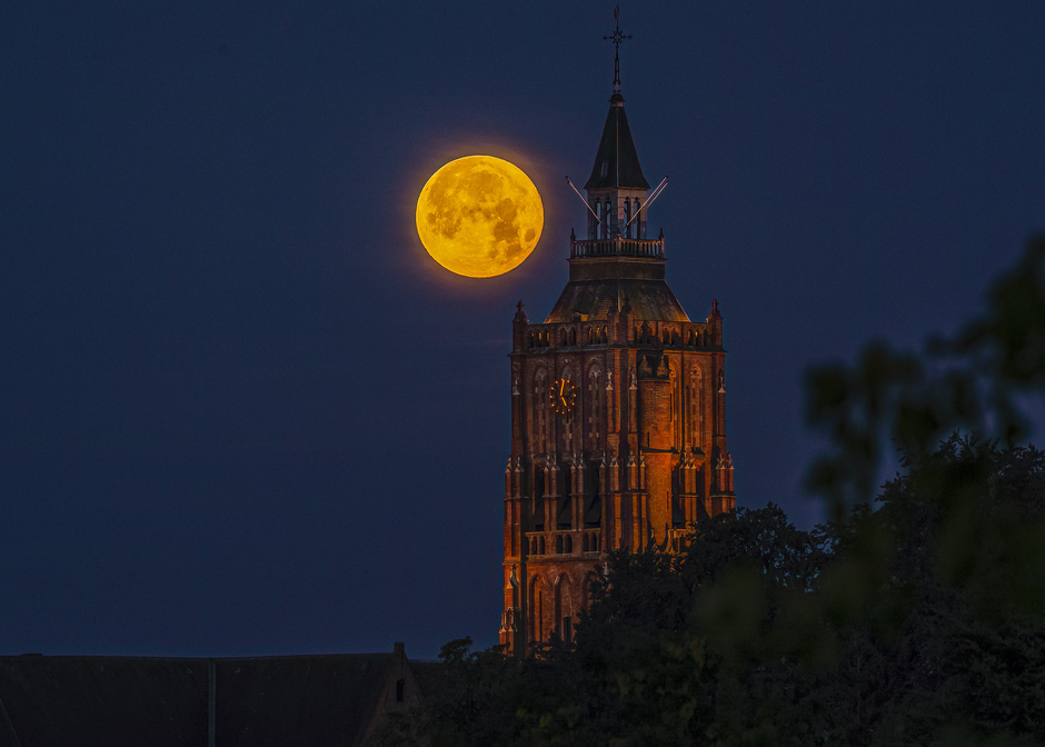 volle maan ondergang naast de kerktoren van Asperen