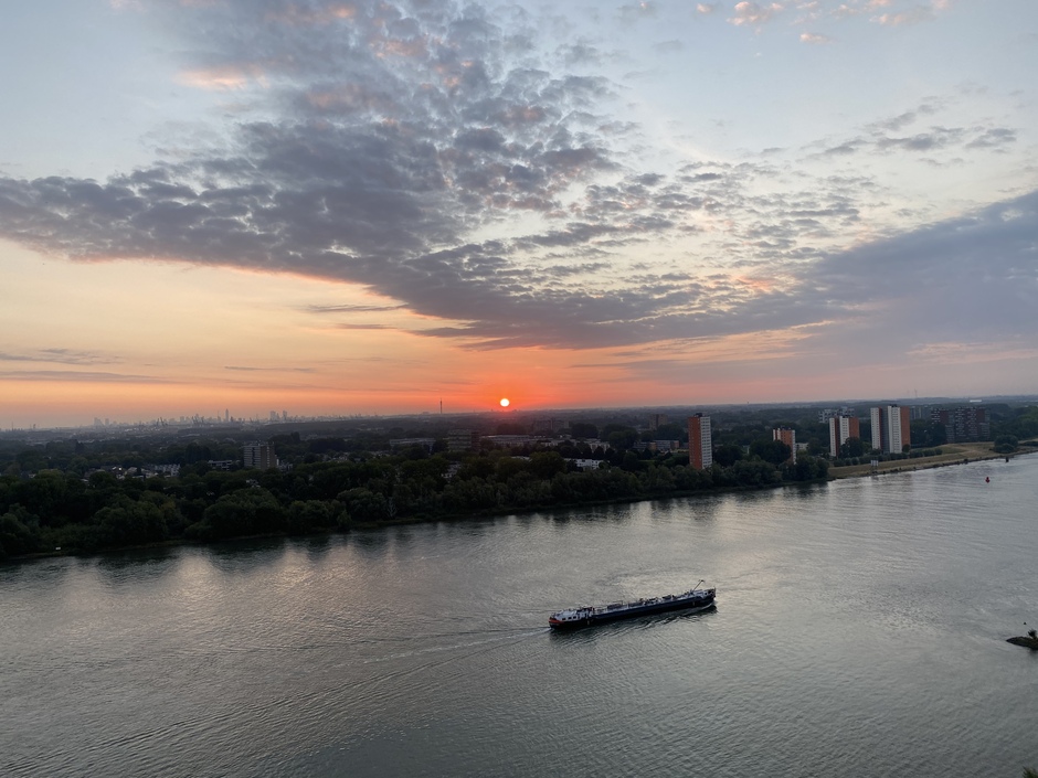 De ochtendgloren met de zon’s op komst aan de oude Maas en de skyline van Rotterdam