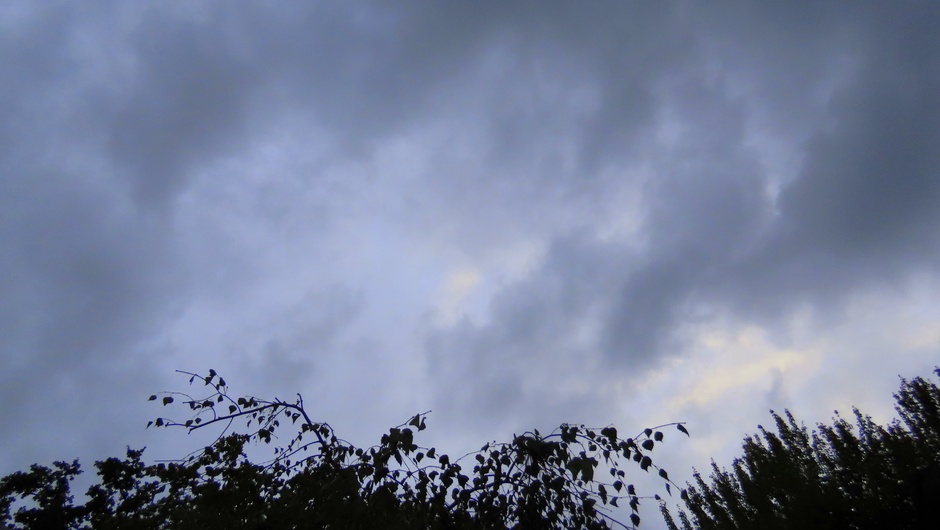 Sprankje kleur in de wolken en de kikker kijkt naar de hoeveelheid regen in de meter