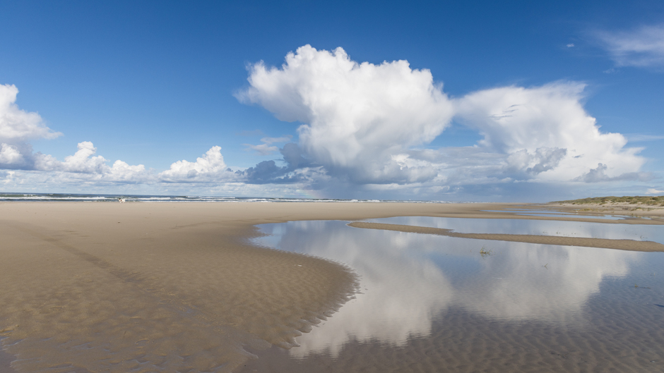 Wolkenspiegel op het strand