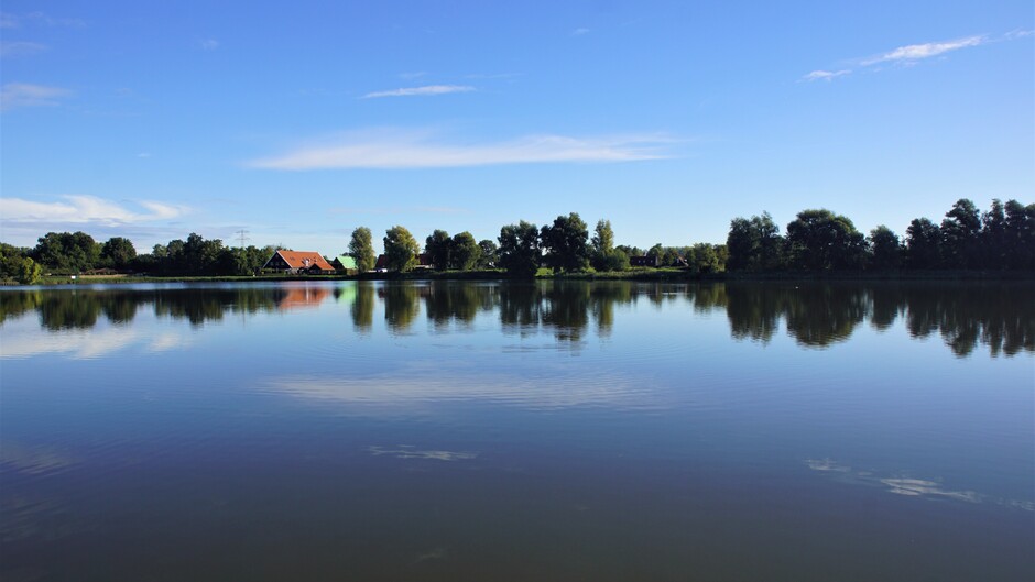 zonnig blauwe lucht wolkjes 11 gr op het meer reflectie