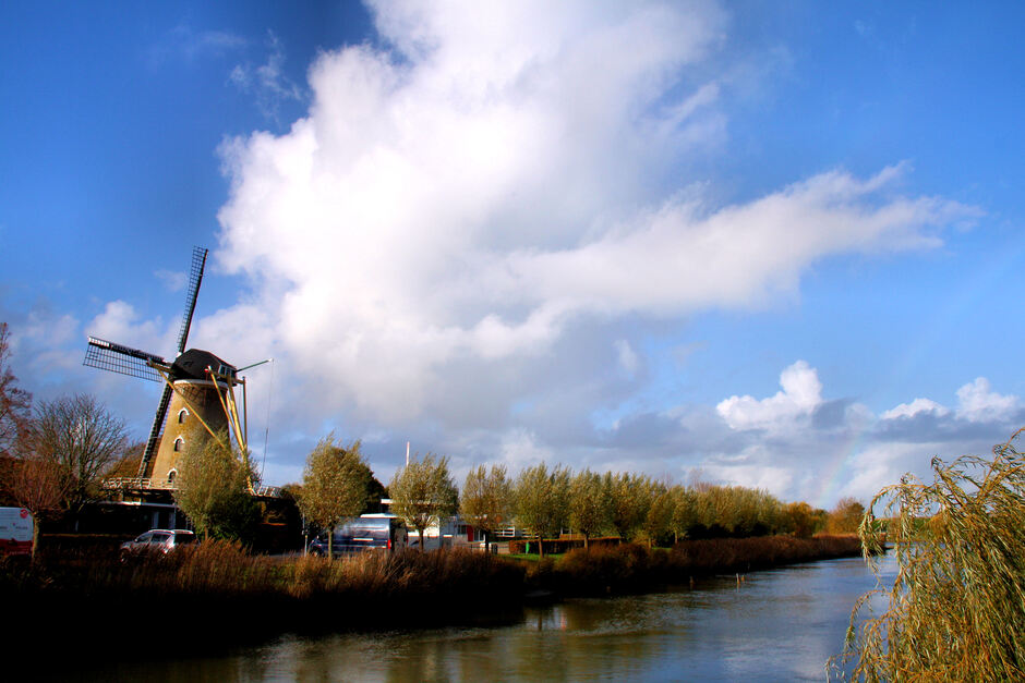 Zonnig, wolken (en in de verte een regenboog) bij molen Nooit Gedacht te Colijnsplaat 