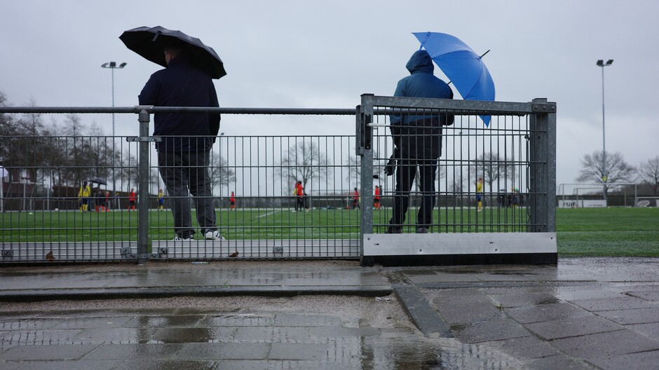 Plassen water, regen en wind langs het voetbalveld 