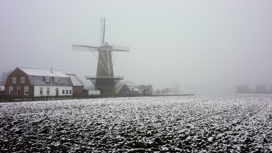 Mistig mystiek winterlandschap met Hollandse molen