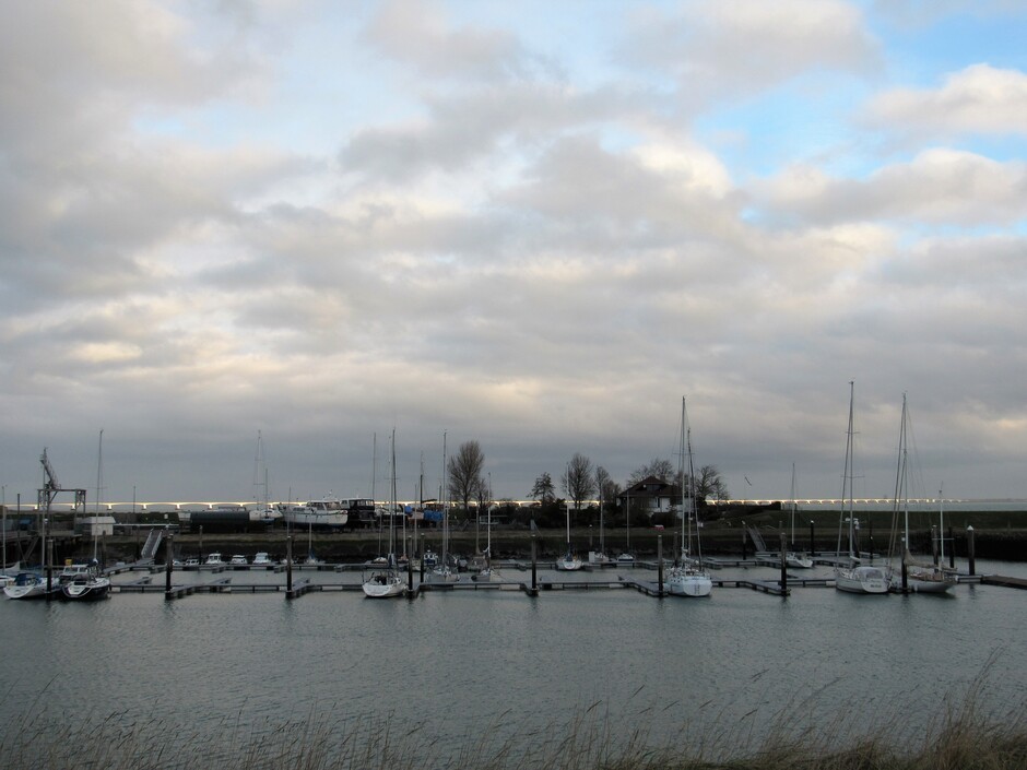 Bewolkt maar de zon schijnt even op de Zeelandbrug die net te zien is achter de Jachthaven bij Kats