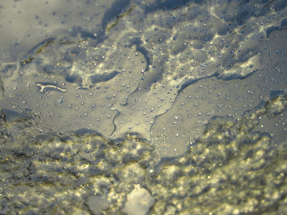 Het ijs smelt in de ochtendzon, op het glazen dak van de auto