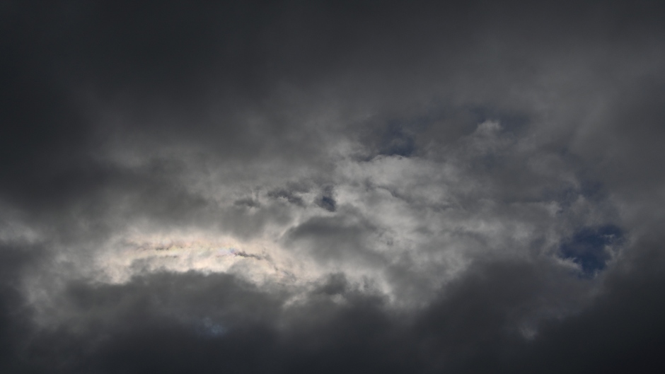 Kleine opening met iriserende wolken achter de grauwe bewolking
