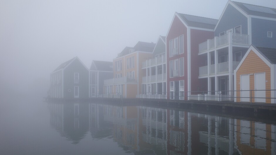 Huisjes die in de mist verdwijnen vroeg in de ochtend 