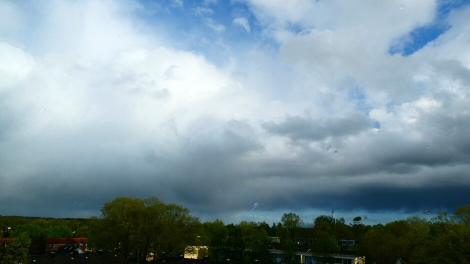 imposante buienwolken en buien met regenboog en opklaringen