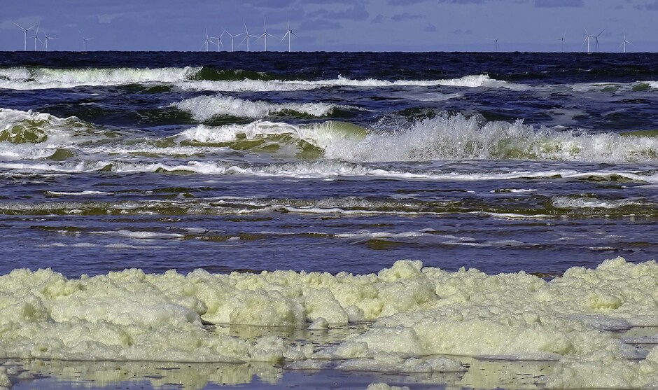 Een strand vol zeeschuim en Hollandse luchten 